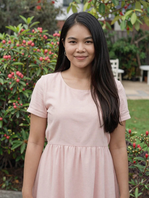 Thai woman in pastel pink dress smiling in a sunny garden - international dating site member preview