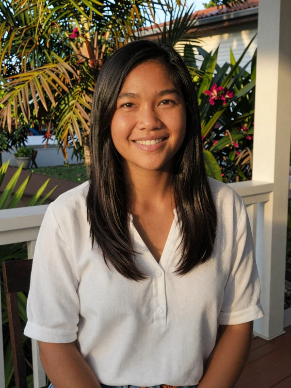 Filipina woman in white linen top smiling on a tropical porch at golden hour - international dating example profile